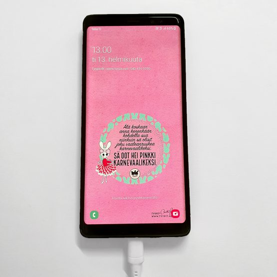 Samsung puhelimeen asennettu vaaleanpunainen Tyypit-taustakuva Pinkki karnevaalikeksi -tekstillä